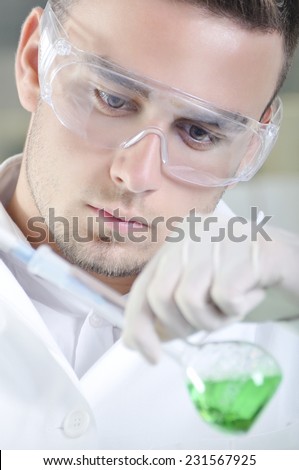 Attractive young PhD student scientist observing the green indicator color shift after the solution destillation in chemical laboratory