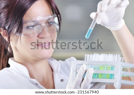 Attractive young PhD student scientist observing the blue indicator color shift after the solution destillation in chemical laboratory