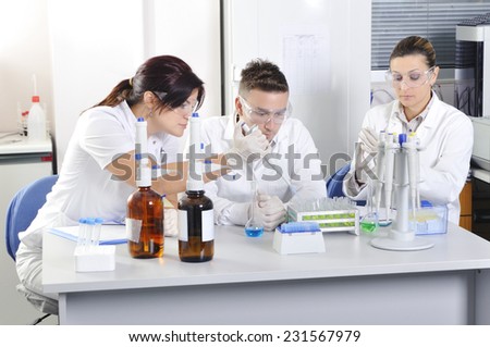 Attractive young PhD students scientists observing the blue, yellow and green indicator color shift after the solution destillation in chemical laboratory