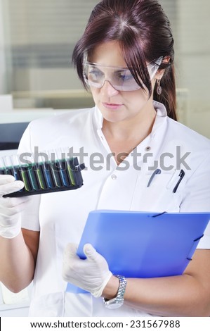 Attractive young PhD student scientist observing the blue, yellow and green indicator color shift after the solution destillation in chemical laboratory