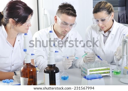 Attractive young PhD students scientists observing the blue and green indicator color shift after the solution destillation in chemical laboratory