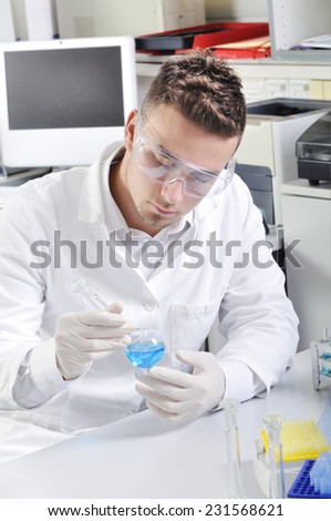 Attractive young PhD student scientist observing the blue indicator color shift after the solution destillation in chemical laboratory