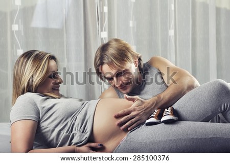 Happy daddy holding pregnant wife\'s belly and smile