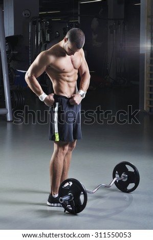 Handsome Muscular Male Model With Perfect Body Posing Next to Barbell