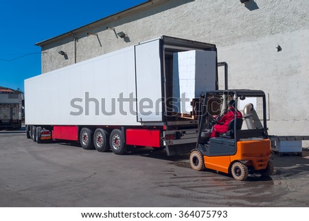 Worker on the loader unload white semi-trailer