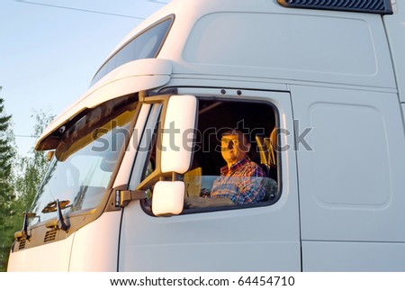 Driver in the cabin of his white truck in the evening