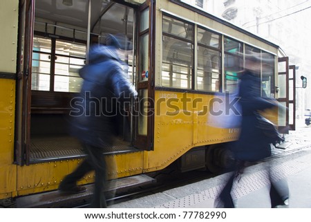 In a hurry, people come down from the tram, high key, blurred for movement, Milano