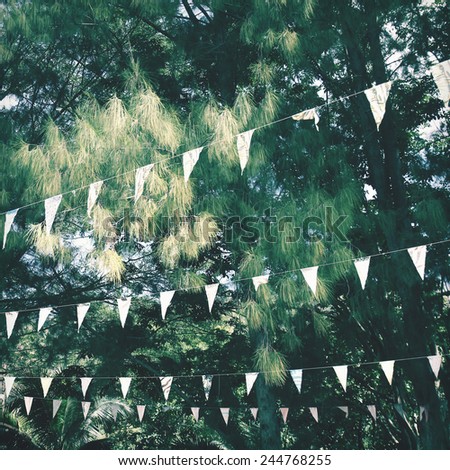 Colorful bunting flags hanging on tree with retro filter effect