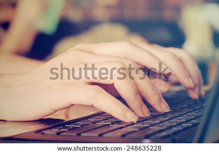 Female hands typing on laptop with retro filter effect