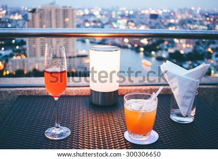 Cocktail glasses with candle light in rooftop bar against city view