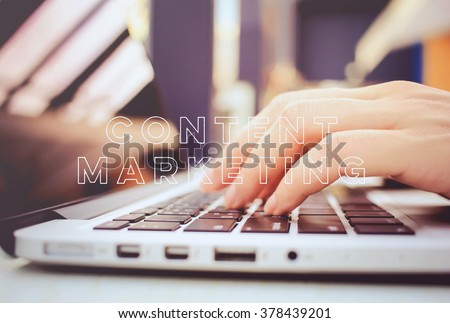 Female hands typing on keyboard of laptop with content marketing word
