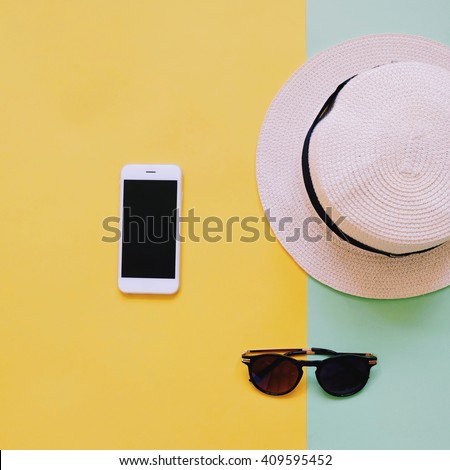 Flat lay fashion of smart phone, panama hat and sunglasses on pastel colorful background