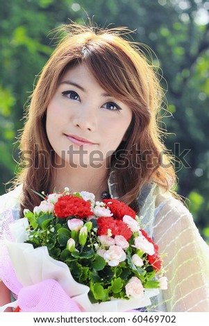 beautiful asian woman holding flower bouquet in the park