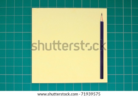 blank yellow paper with pencil on a green cutting mat