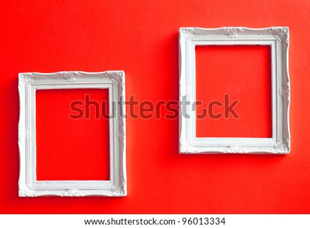 Two white vintage frames on red wall