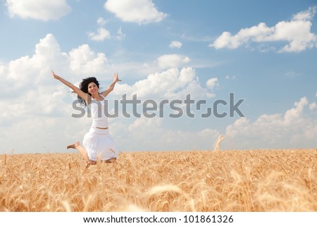 Happy woman jumping in golden wheat