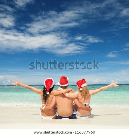 Happy friends in santa hats on the beach. Christmas vacation