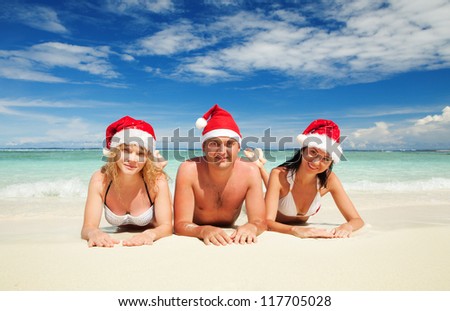 Happy friends in santa hats on the beach. Christmas vacation