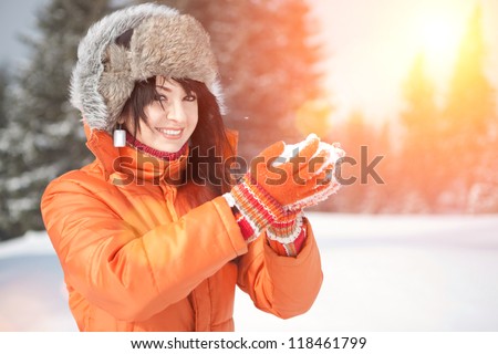 Happy girl playing with snow in the winter landscape