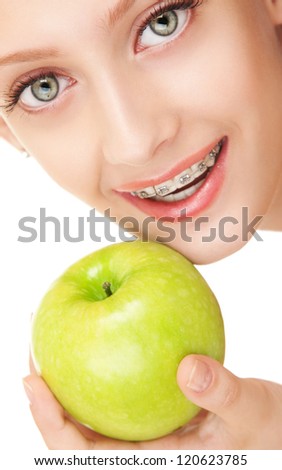 Cute girl in braces with green apple on white background