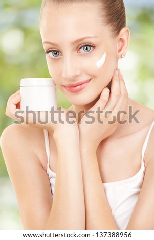 Cute woman applying cream to her face