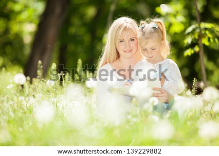 Mother and daughter drawing on grass in park