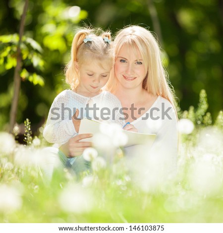 Mother and daughter drawing on grass in park