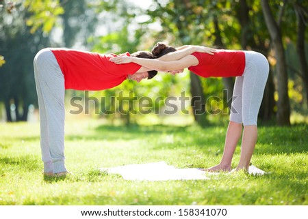 Couples Yoga, man and woman doing yoga exercises in the park