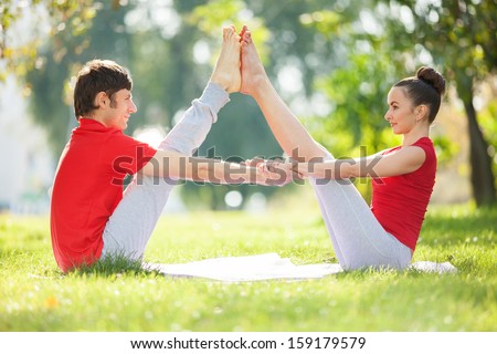 Couples Yoga, man and woman doing yoga exercises in the park