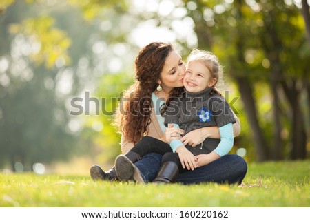 Mother Kissing Her Daughter In The Park