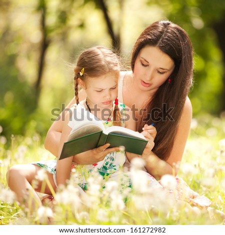 Mother with daughter read the book in the park