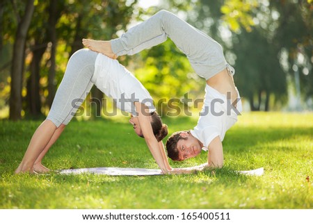 Couple Yoga, man and woman doing yoga exercises in the park