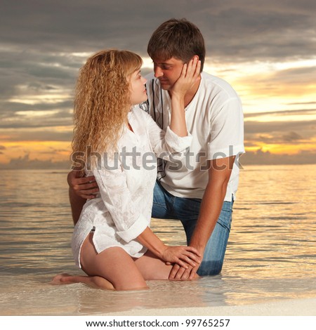 Young couple on the sea sunset background