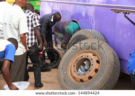 MBARARA, UGANDA - SEPTEMBER 27, 2012. A bus maintenance worker changes the back tires and brakes of  broken down Horizon Bus #88 in Mbarara, Uganda on September 27, 2012.