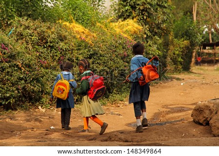 SUYE, TANZANIA - SEPTEMBER 10 : Three young African schoolgirls walk home from school in their uniforms in Suye, Tanzania on September 10, 2012.  Nearly all schools in Tanzania require uniforms.