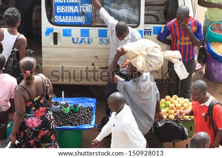 KAMPALA, UGANDA - SEPTEMBER 28, 2012.  A line of passengers enter into a mini-bus while passing different types of food for sale in the main taxi park in Kampala, Uganda on September 28,2012.