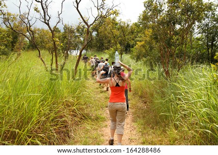 Murchison Falls, Uganda - September 30, 2012. A Woman Balances Water On Her Head While Hiking With A Tourist Group Through The Jungle Near Murchison Falls, Uganda On September 30, 2012.