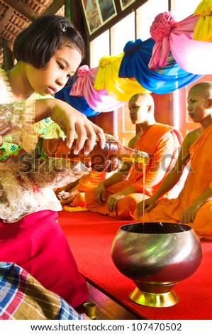 SAMUT SAKHON,THAILAND-SEPT 23:Unidentified thai children in native dress give the honey to monks in the tradition of giving alms Buddhist monks with honey on September23,2010 in Samut Sakhon,Thailand