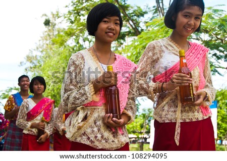SAMUT SAKHON,THAILAND-SEPT 23:Unidentified thai children in native dress give the honey to monks in the tradition of giving alms Buddhist monks with honey on September23,2010 in Samut Sakhon,Thailand