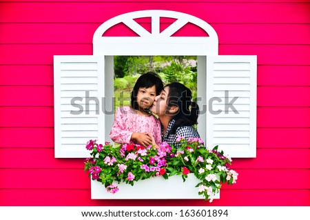 Asia mother kissing daughter on window in house of love