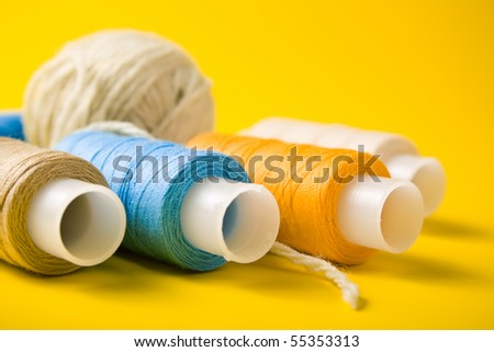 ball of yarn and spools of thread on a yellow background