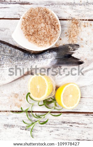 Fish tail with lemon, sea salt, fresh lemon on white wooden textured background. Culinary seafood background in white.