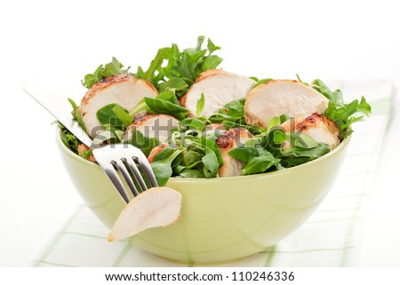 Delicious lamb\'s lettuce salad with chicken in green bowl, piece of chicken on silver fork. Luxurious healthy summer meal.