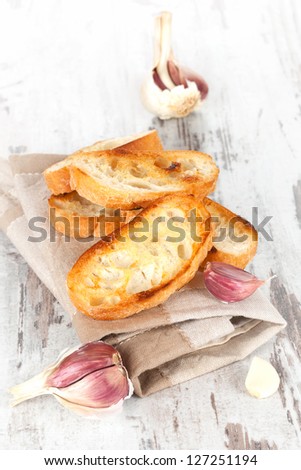 Garlic bread with fresh garlic on white wooden textured background. Culinary healthy eating, french country style.