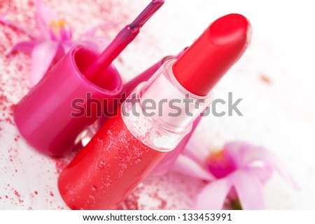 Red lipstick, pink nail polish, face powder and pink flower on white background. Luxurious glamour cosmetics background in red and pink