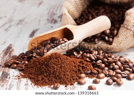 Traditional coffee background. Ground coffee and coffee beans on white wooden textured background. Culinary aromatic coffee drinking.