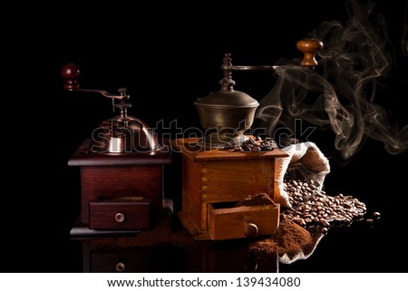 Old vintage wooden coffee mills with ground coffee, sack with coffee beans and the smell of fresh coffee isolated on black background. Culinary aromatic coffee background.