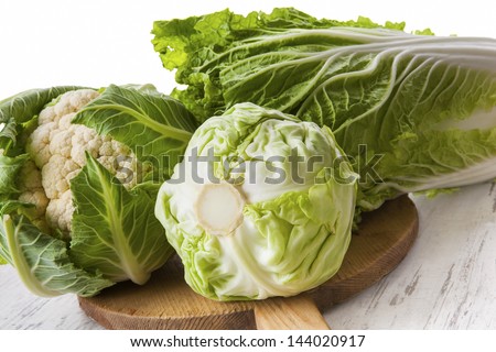 Cabbage family. Cauliflower, chinese cabbage and cabbage on wooden cutting board. Bright healthy green vegetable background. Healthy summer eating.