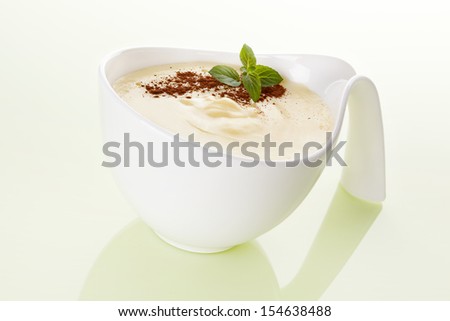 Delicious vanilla pudding with fresh mint and cocoa powder in white bowl isolated. Culinary sweet eating.