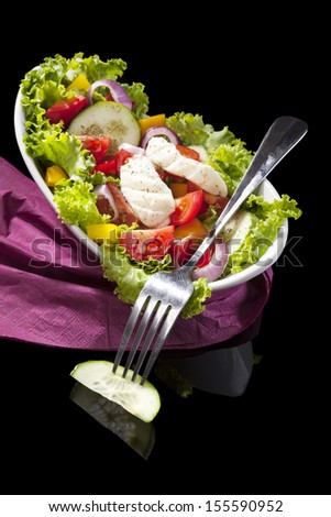 Luxurious colorful greek salad with colorful vegetable and feta cheese in bowl isolated on black background. Healthy eating.